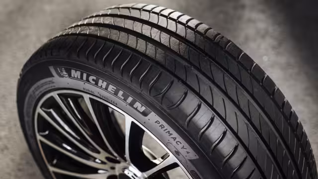 Detail skutečné pneumatiky Michelin s viditelnými drážkami po celé šířce běhounu